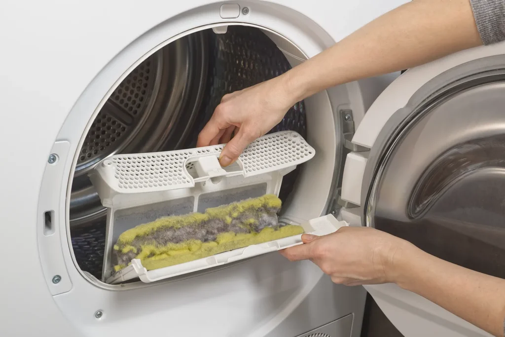 A person using a brush to clean a dryer vent, illustrating the cleaning process for a Hotpoint dryer vent and duct.