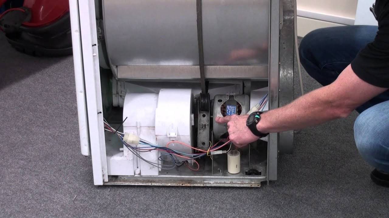 A person checking the inside of a Hotpoint dryer with a flashlight, illustrating the troubleshooting process for a Hotpoint dryer not heating.